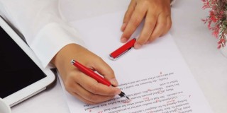person proofreading a paper with a red pen